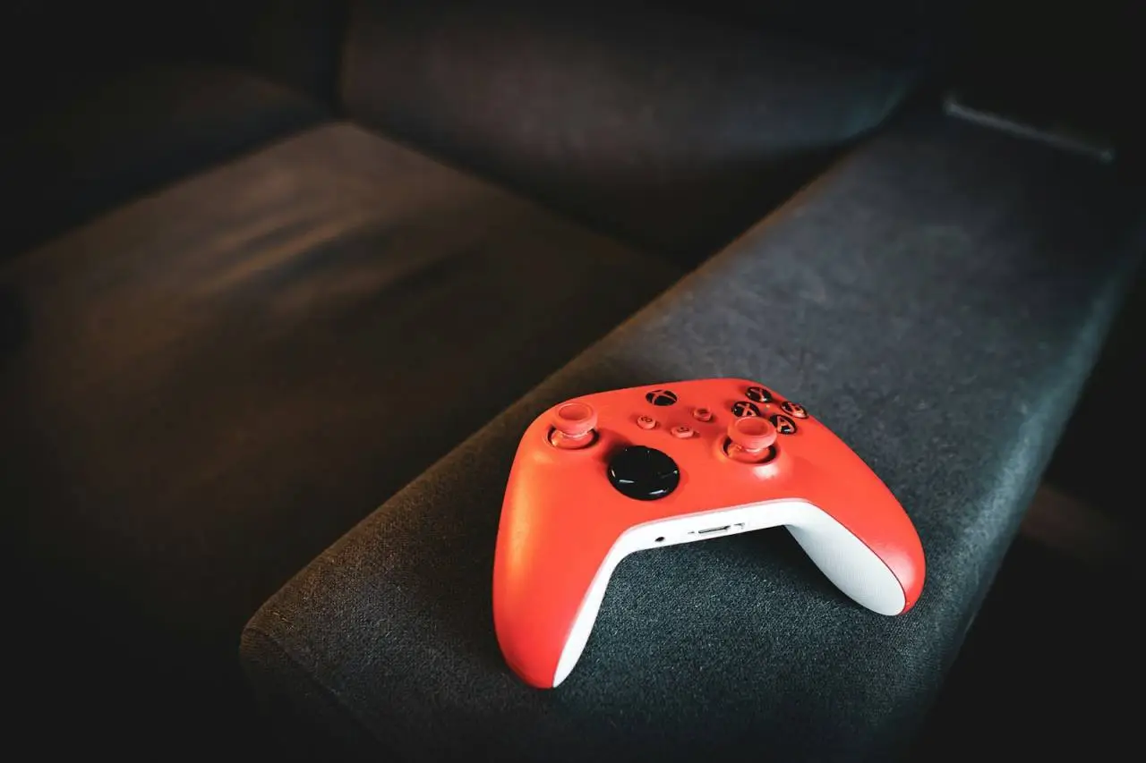 Red video game controller rests on a dark couch